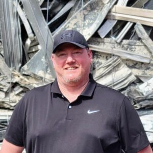 Scott Hayden standing in front of a metal bale of aluminum