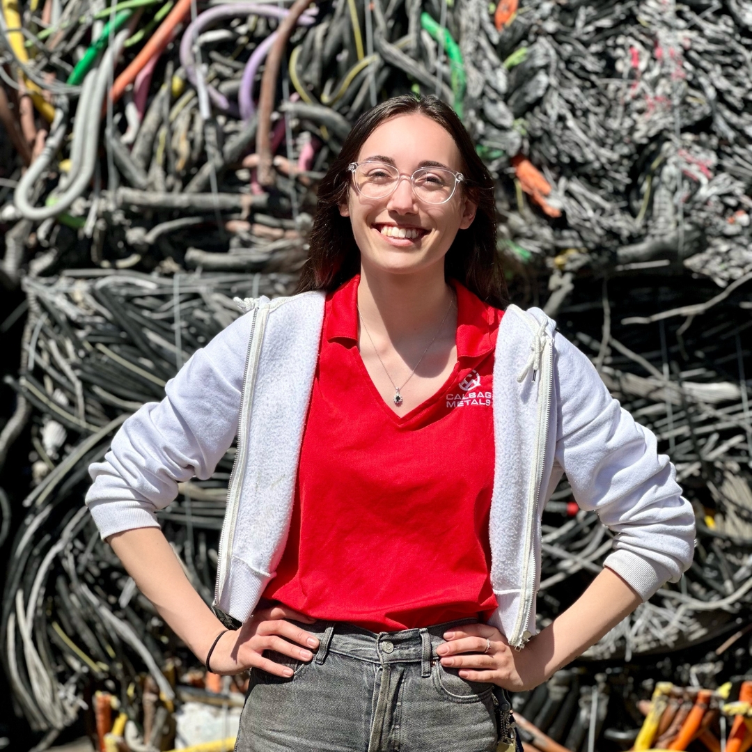 Lexi Redinger standing in front of metal wire bales